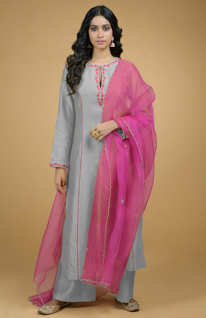 A woman models a blue kurta set with a magenta organza dupatta.