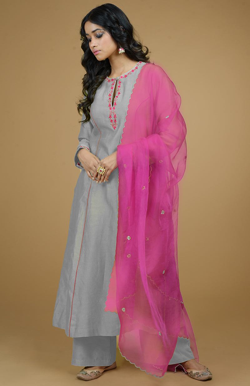 An ash grey kurta set with magenta embroidery and a matching organza dupatta.