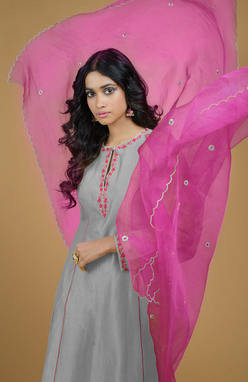 An ash grey kurta set with magenta embroidery and a flowing magenta organza dupatta.