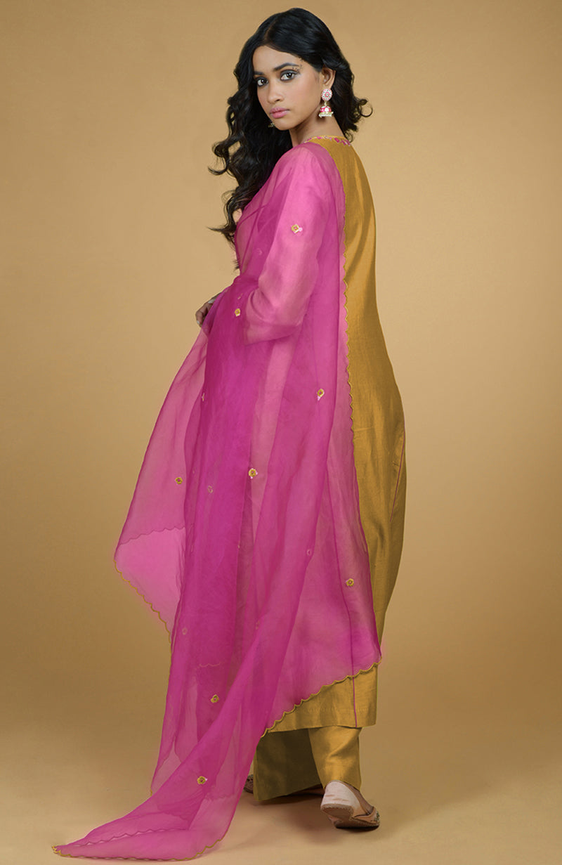 A woman models a mustard kurta set with a magenta organza dupatta.