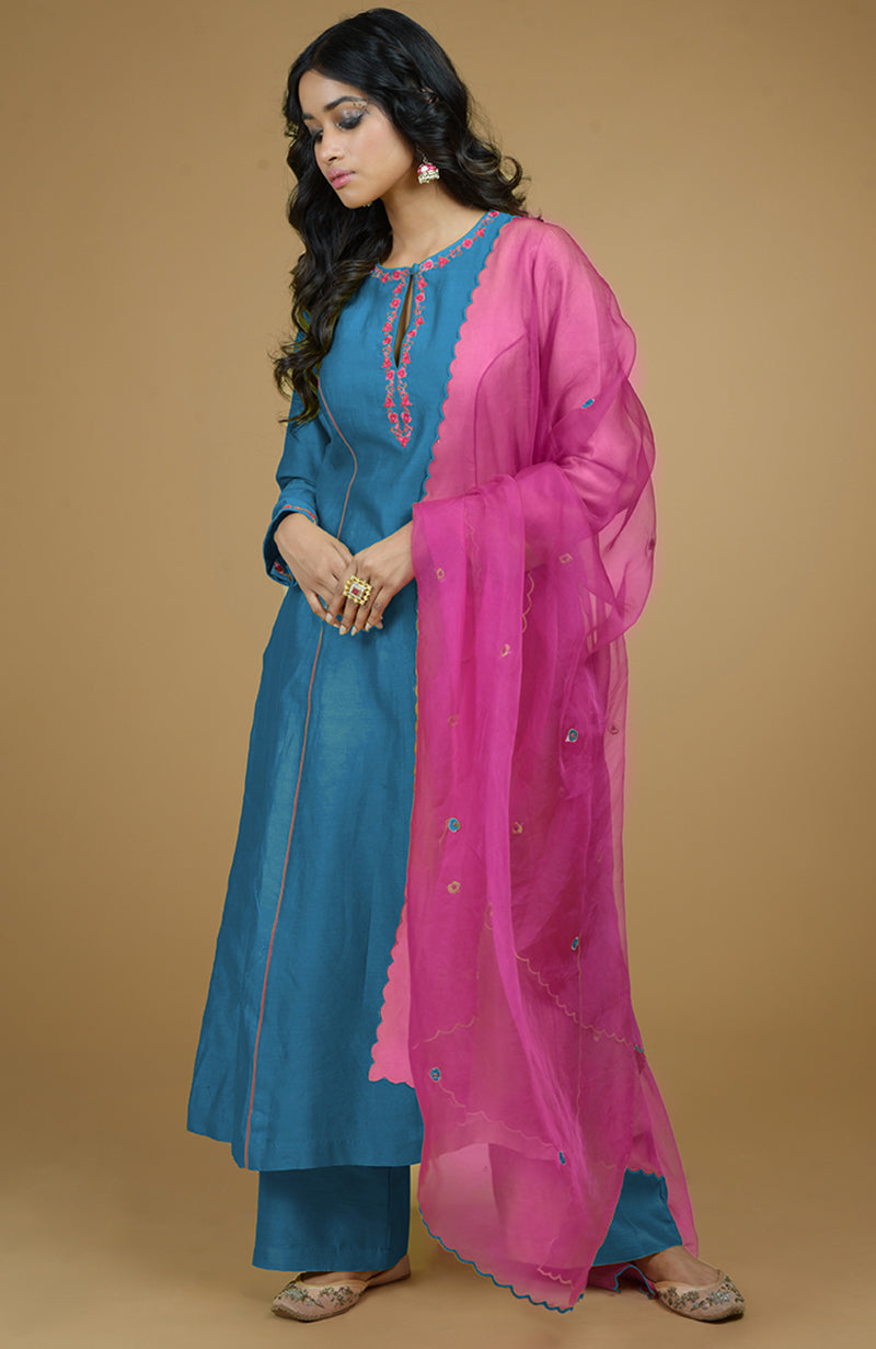 A woman models a blue kurta set with a magenta organza dupatta.