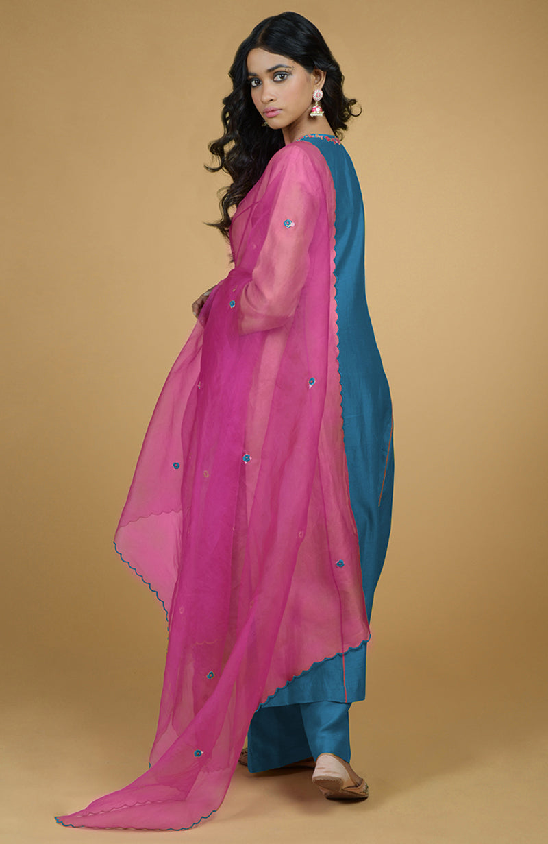 A woman models a blue kurta set with a magenta organza dupatta.