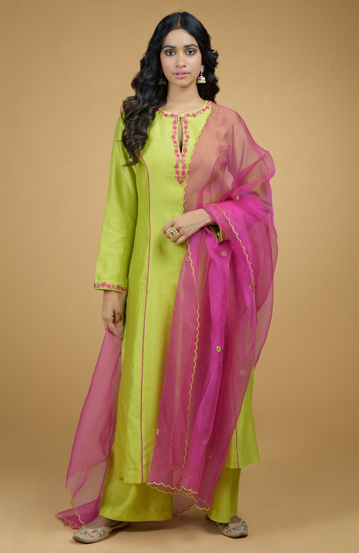 A woman models a beige and magenta organza kurta set with a lime green dupatta.
