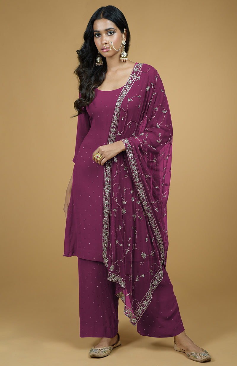A woman models a peacock pink kurta set with silver mukaish and zardozi embroidery.