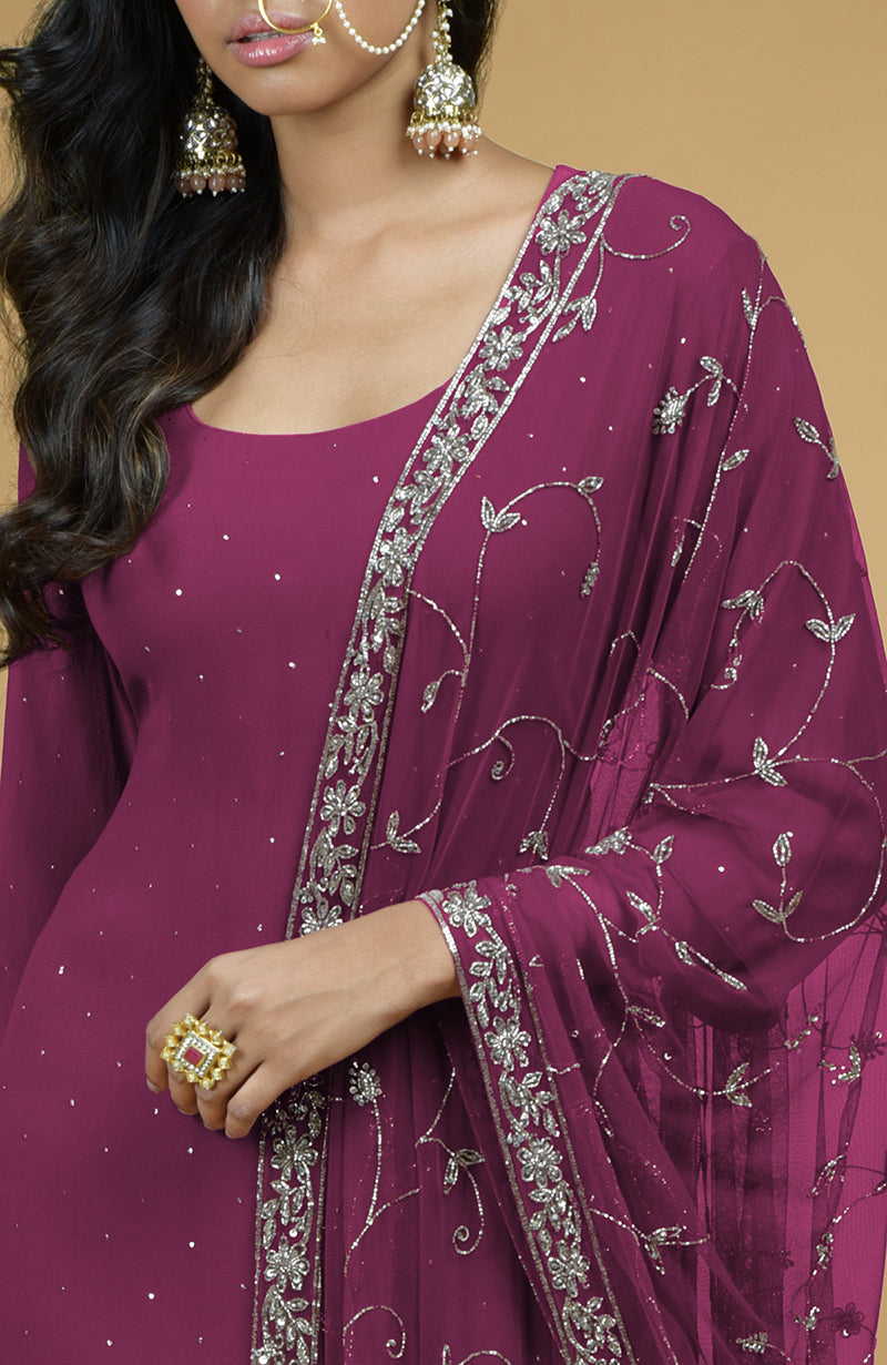A woman models a peacock pink kurta set with silver embroidery and a matching dupatta.