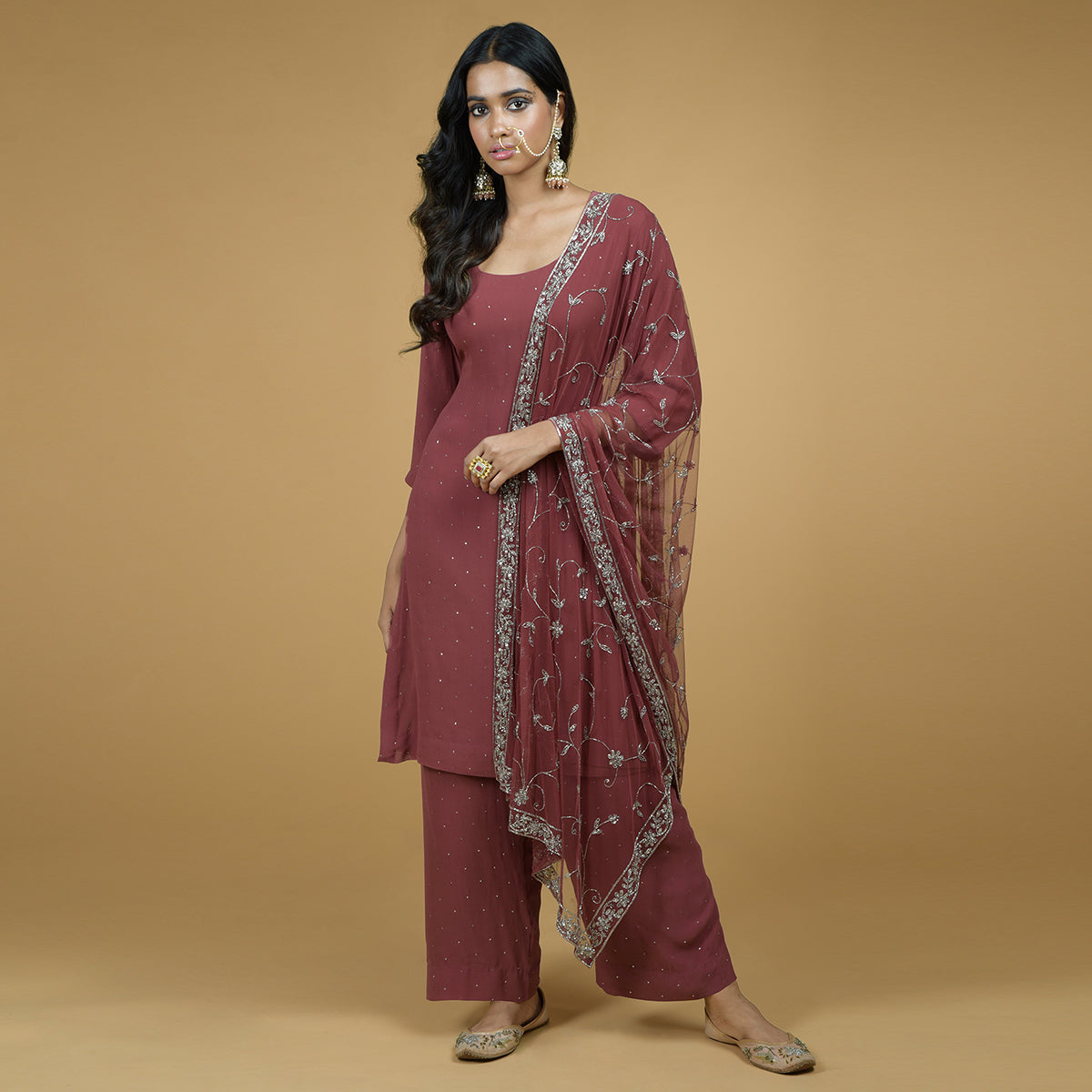 A woman models a peacock pink kurta set with silver zardozi hand embroidery.