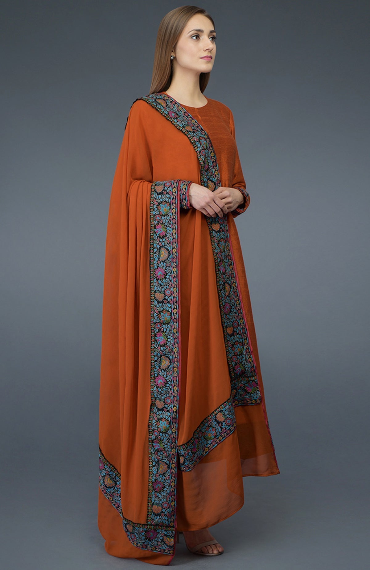 Burnt orange raw silk suit with jewel neckline and multicolor Kashmiri hand embroidery on shirt and dupatta.
