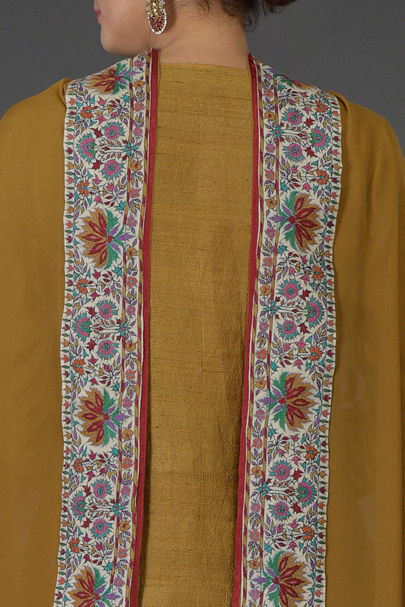 Dark mustard raw silk suit with multicolor Kashmiri hand embroidery and georgette dupatta borders.