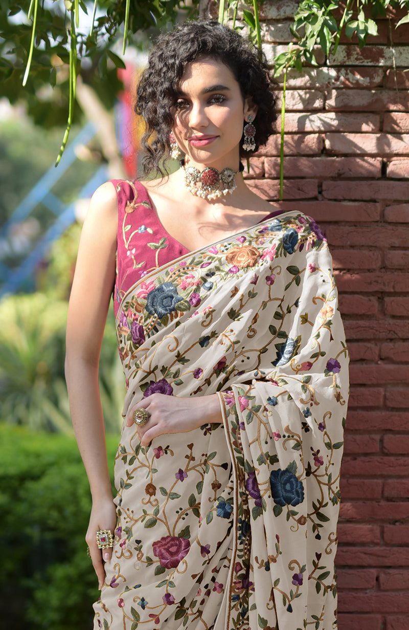 Cream floral Parsi Gara hand-embroidered saree with a wine-colored blouse.