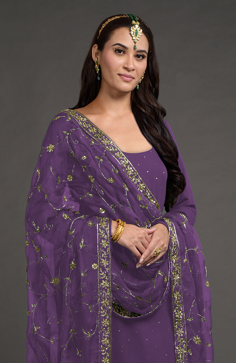 Woman in an amethyst mukaish-zardozi embroidered kurta set with a maang tikka.