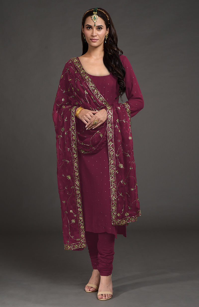 A woman models a wine-colored kurta set with gold mukaish and zardozi embroidery.