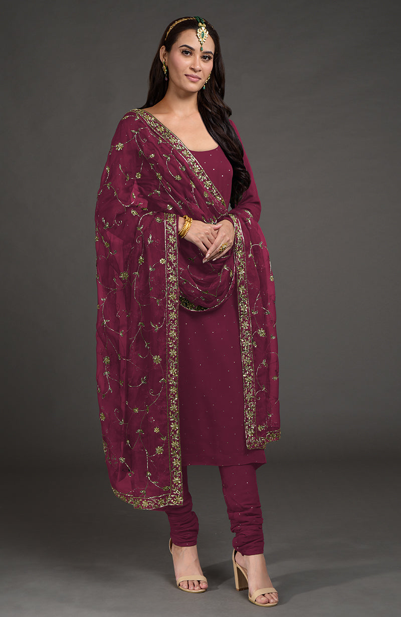 A woman models a wine-colored kurta set with gold mukaish and zardozi embroidery.
