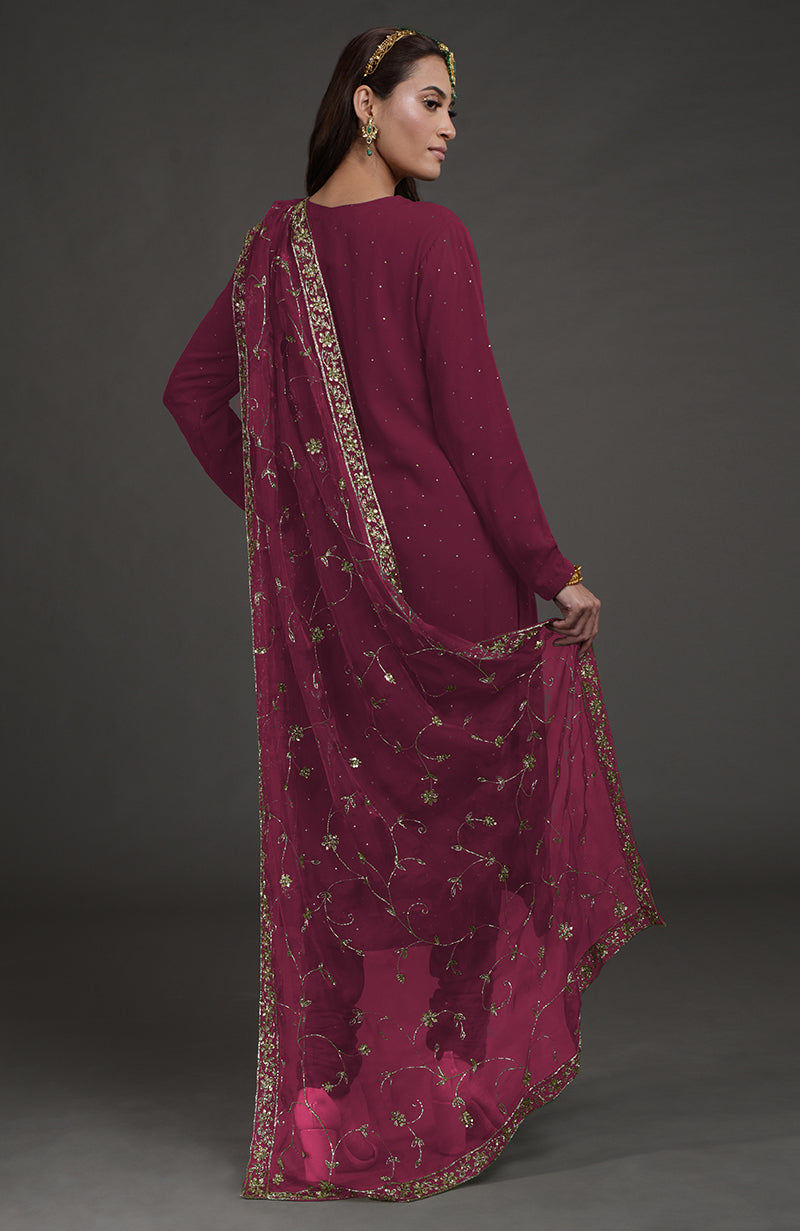A woman models a wine-colored kurta set with gold mukaish and zardozi embroidery.
