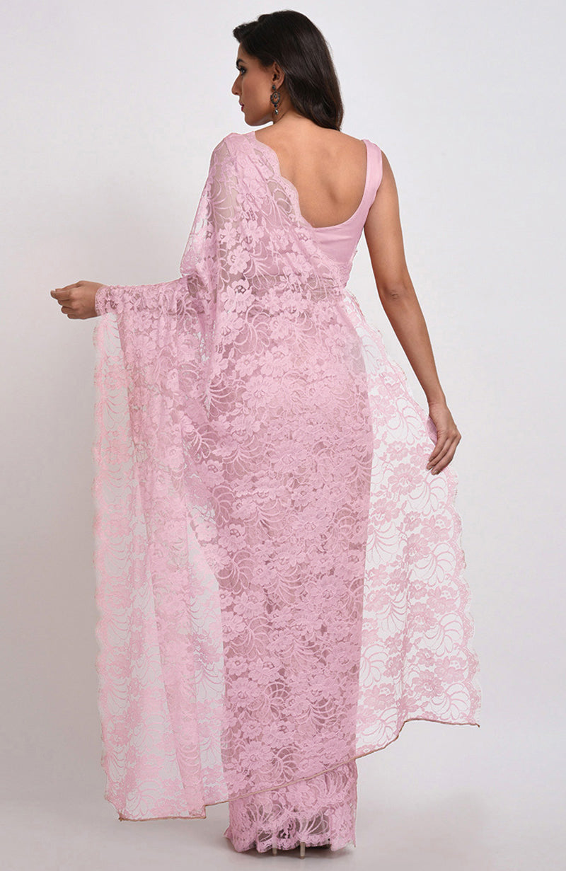 A woman models a pink French Chantilly lace saree with a matching blouse.
