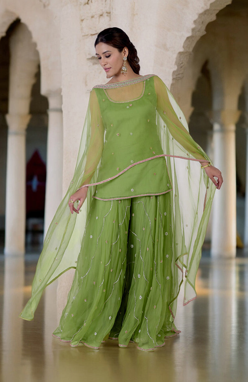 A woman models a lime green hand-embroidered sharara cape set.