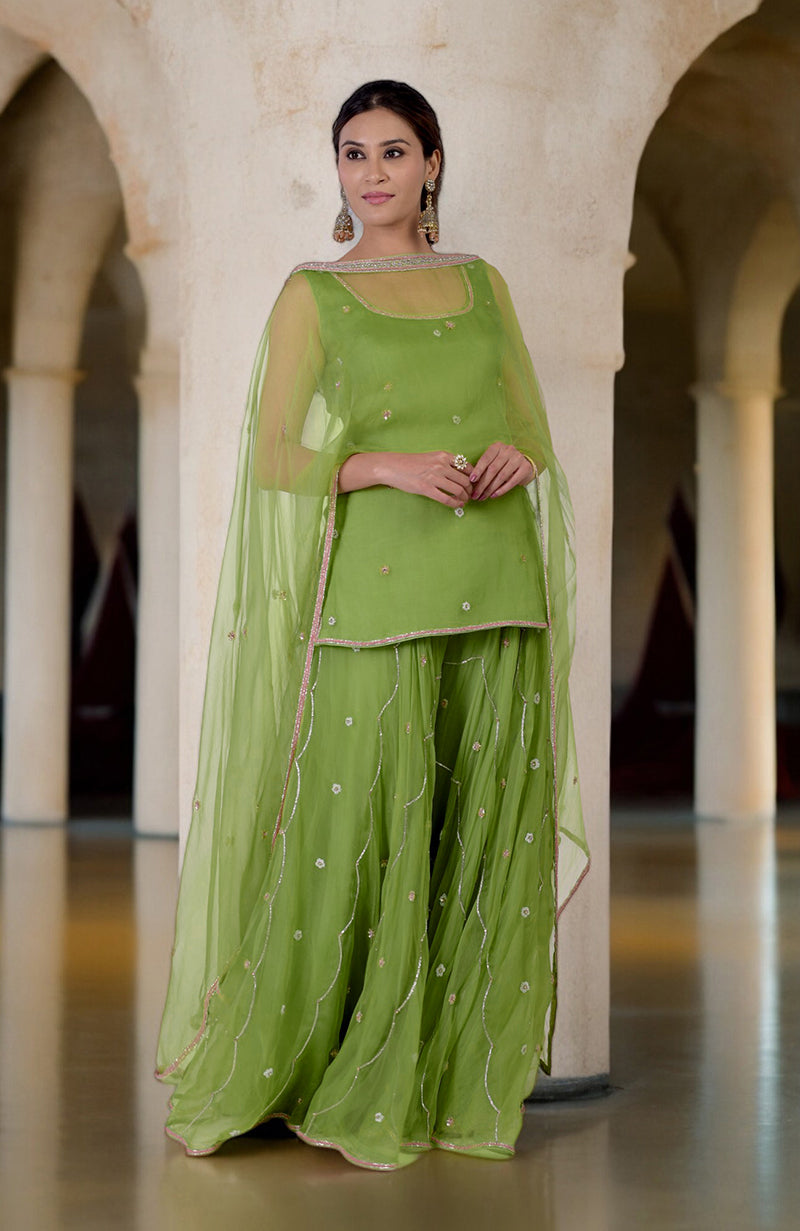 A woman models a lime green hand-embroidered sharara cape set.
