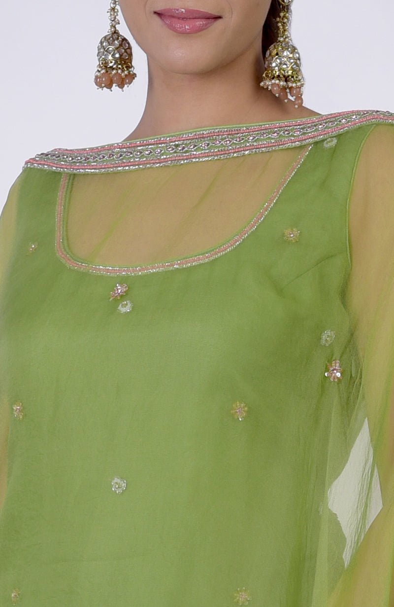A woman wears a lime green hand-embroidered sharara cape set with pink and silver accents.