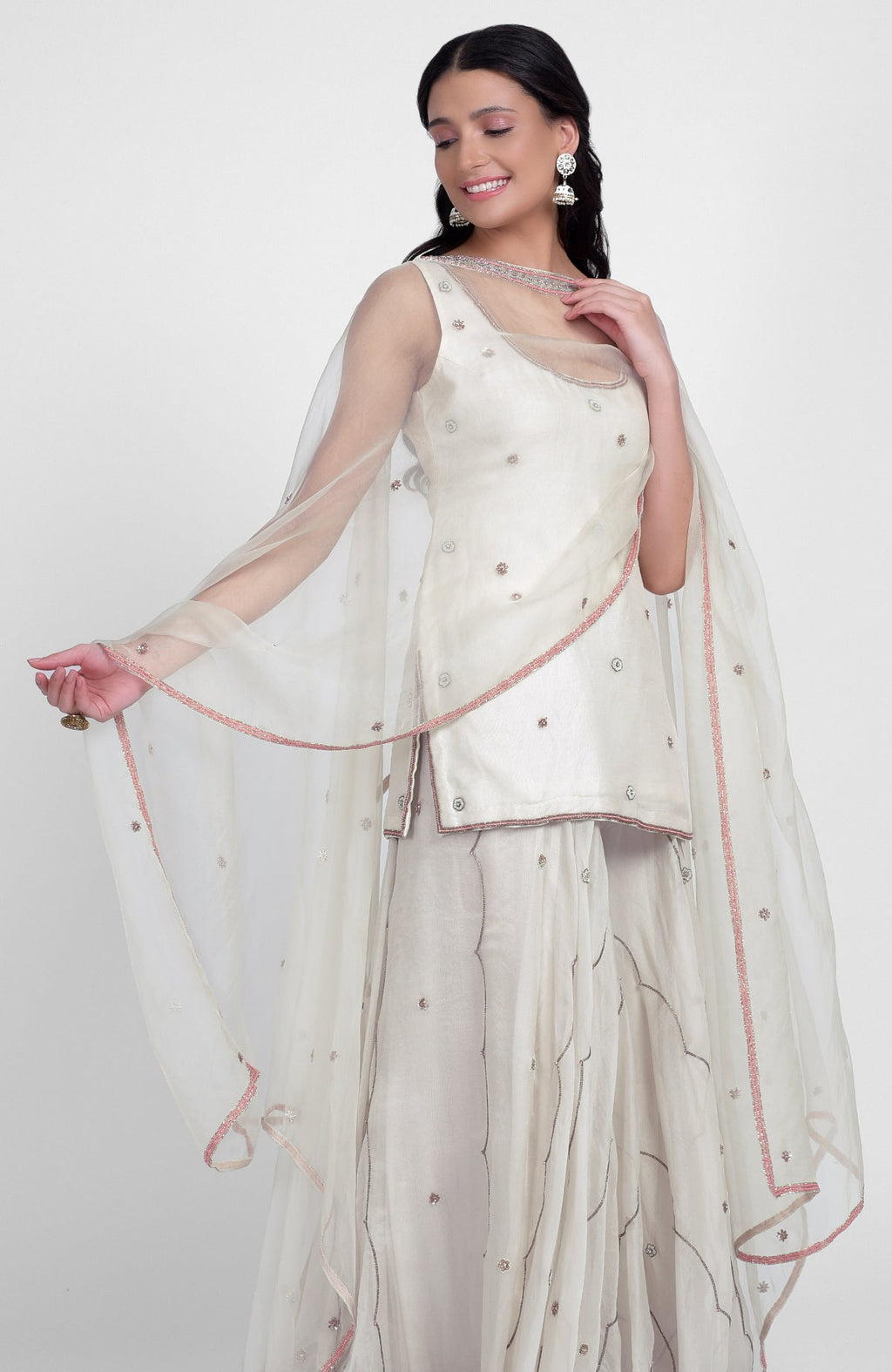 Off-white silk sharara set with pastel hand embroidery, scoop neck kurta, and cape dupatta