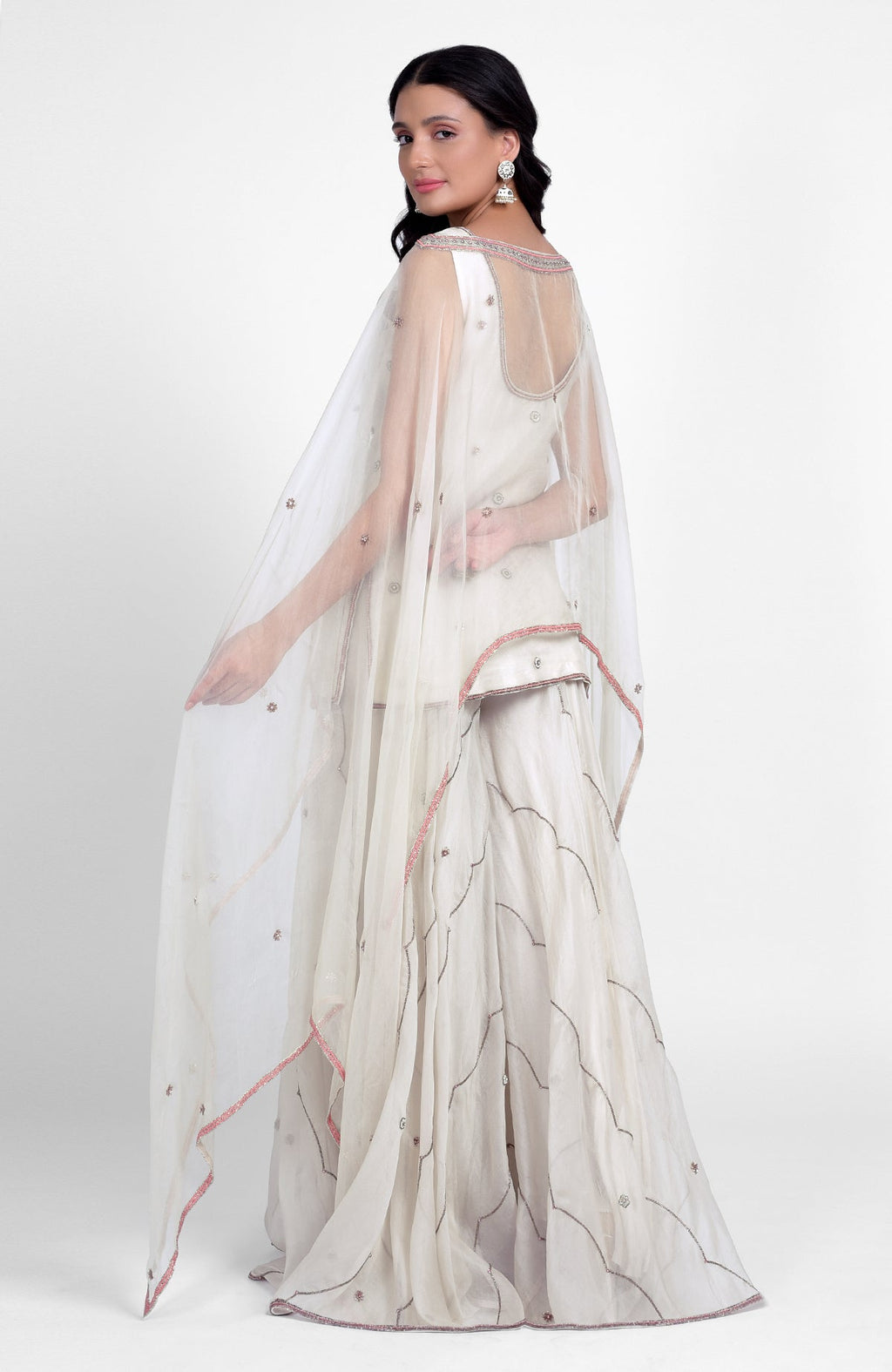 Off-white silk organza sharara set with pastel embroidery, scoop neck kurta, and cape dupatta.