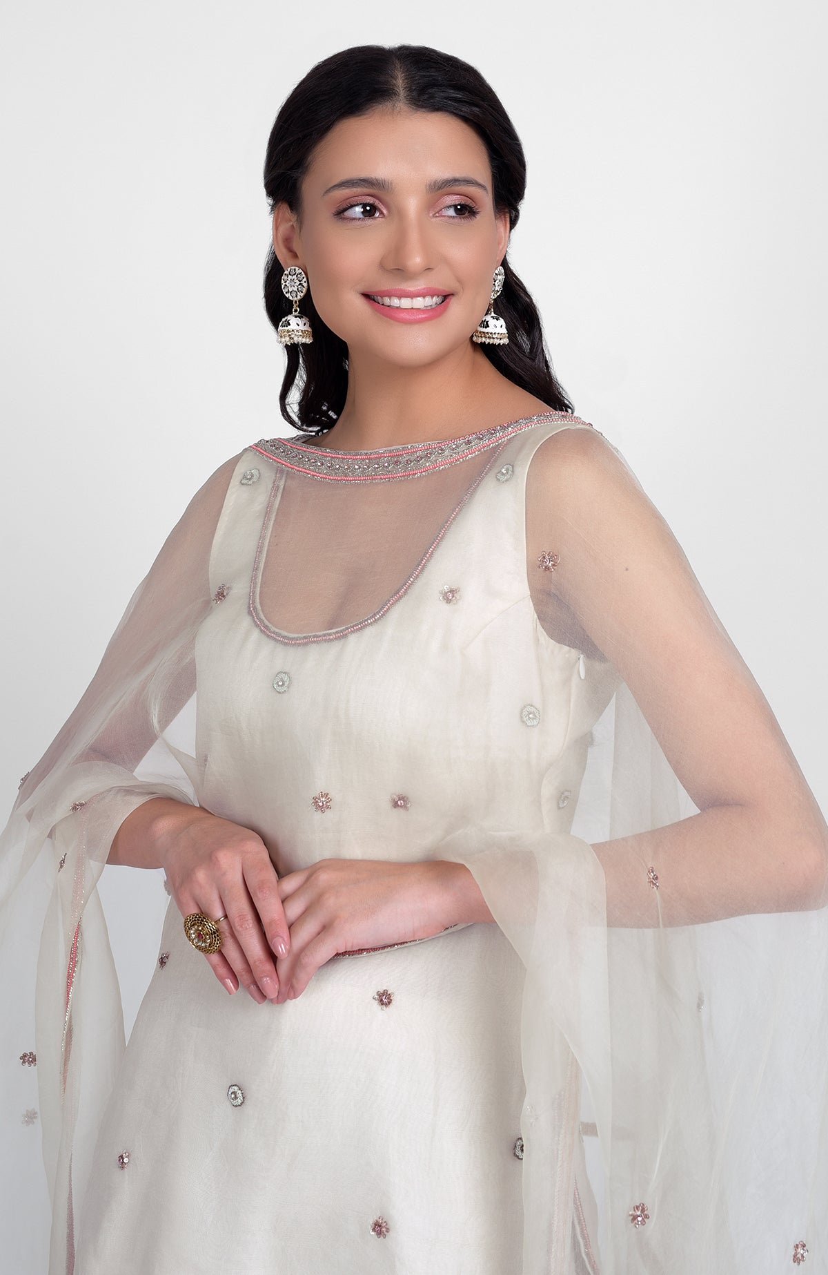 Off-white silk organza sharara set with pastel hand embroidery, scoop neck kurta, and cape dupatta