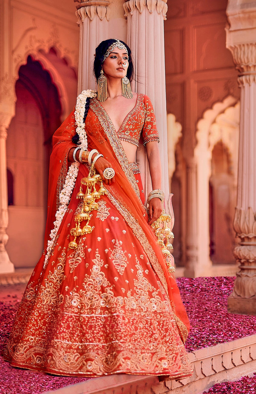 Red lehenga set with gold floral embroidery, sweetheart neckline, and tasseled open back blouse.