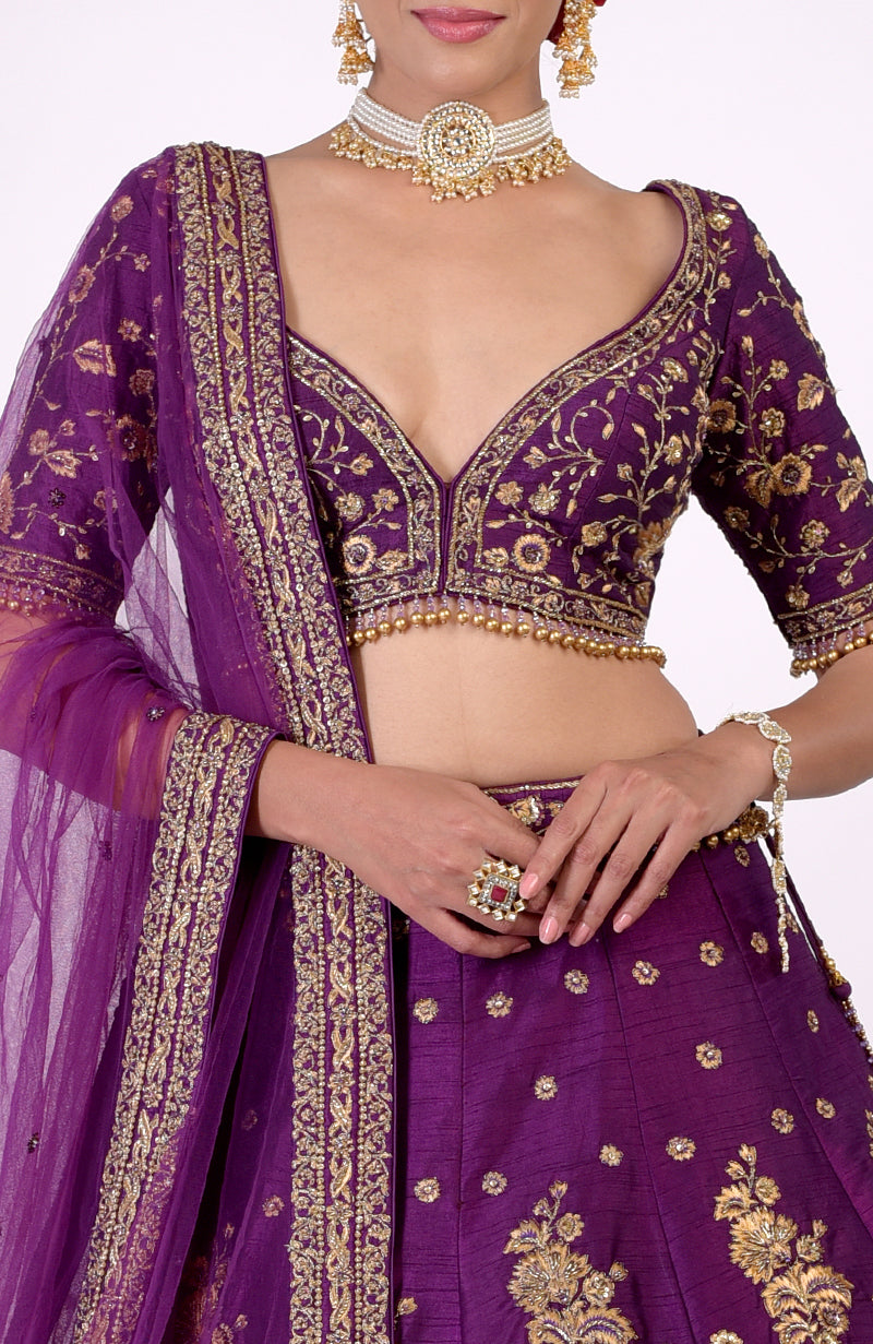 Plum lehenga set with gold embroidery and a deep V-neck blouse.