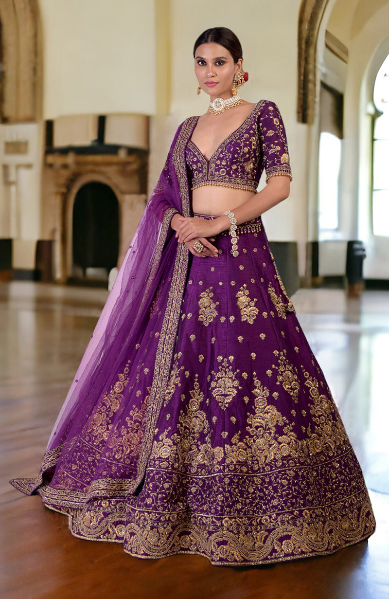 A woman models a purple lehenga set with gold embroidery and a sheer dupatta.