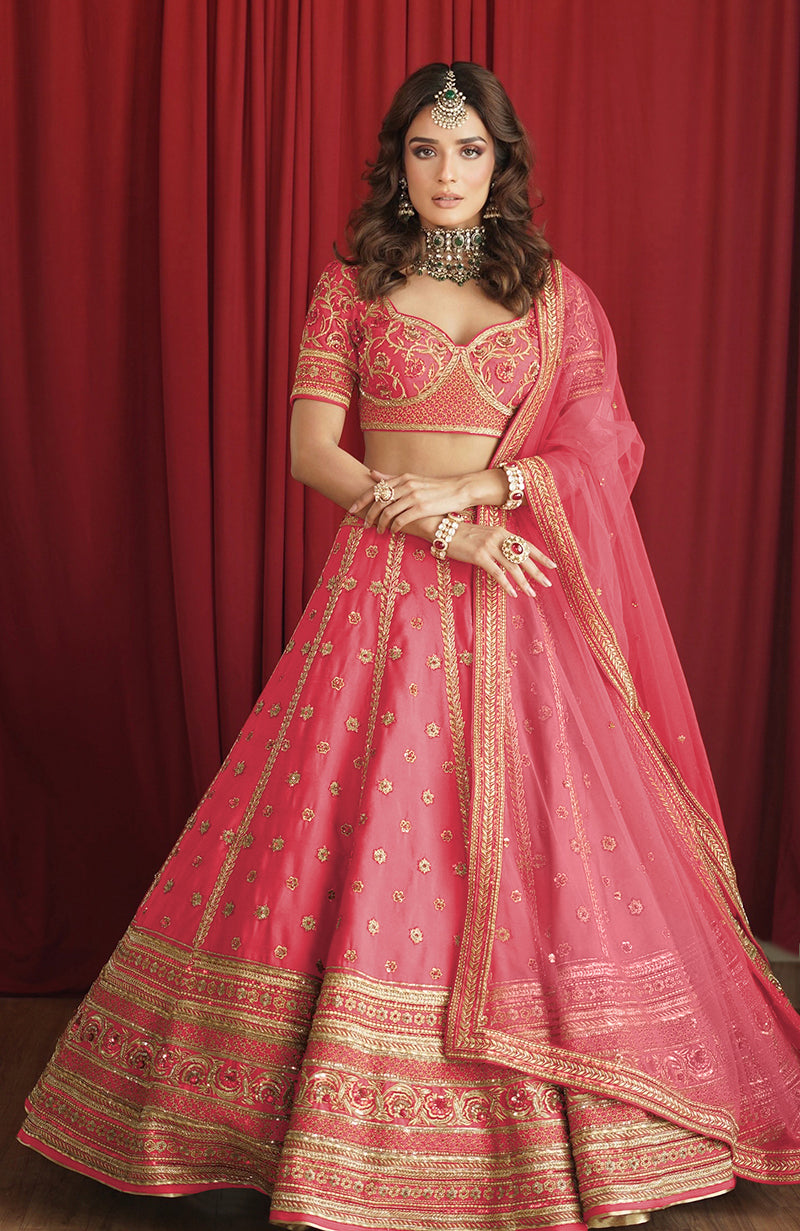 A woman models a boysenberry lehenga set with gold embroidery and a sheer dupatta.