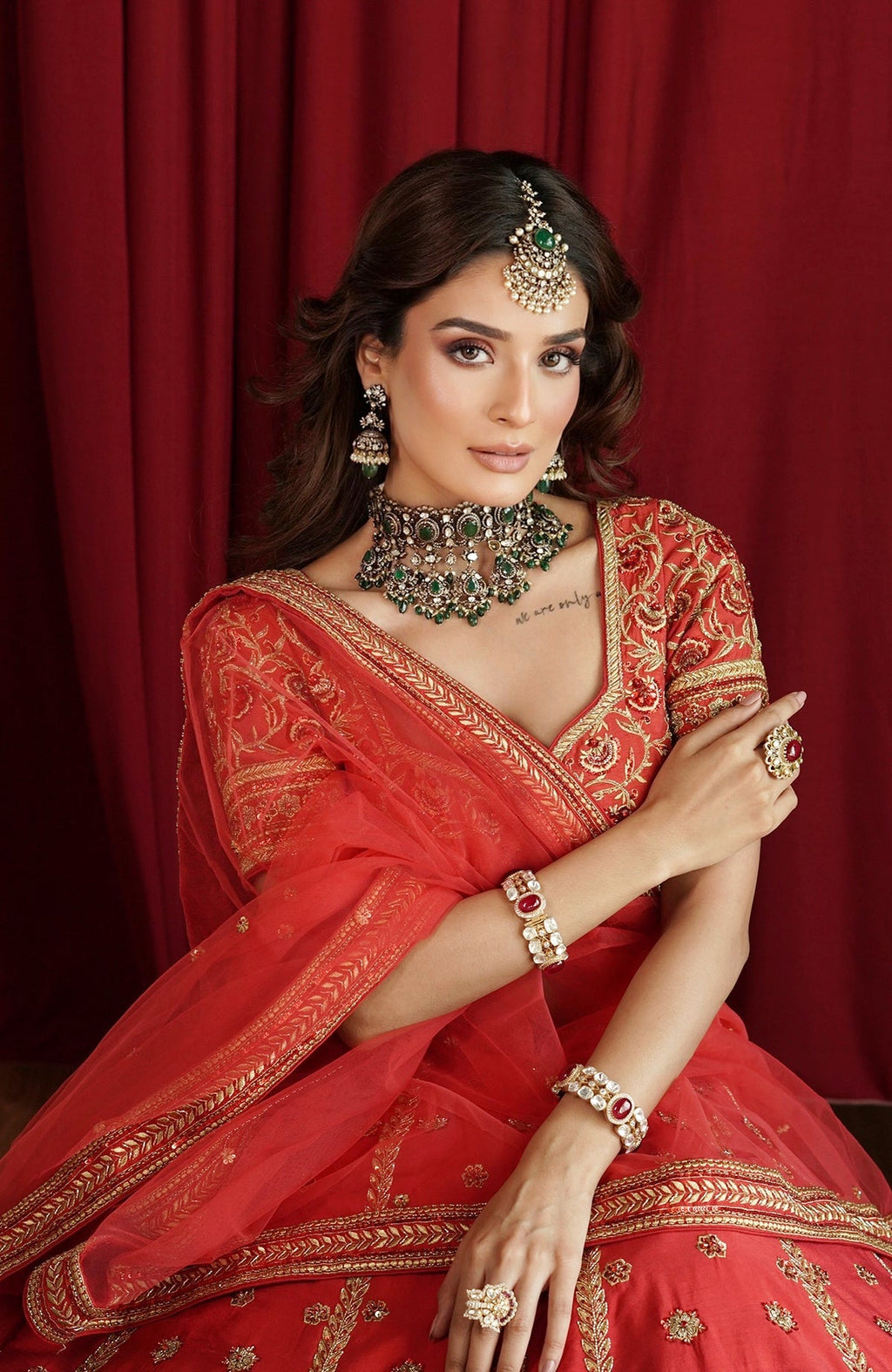 Scarlet red lehenga set with gold kasab and zardozi embroidery and a stylized V-neck blouse.