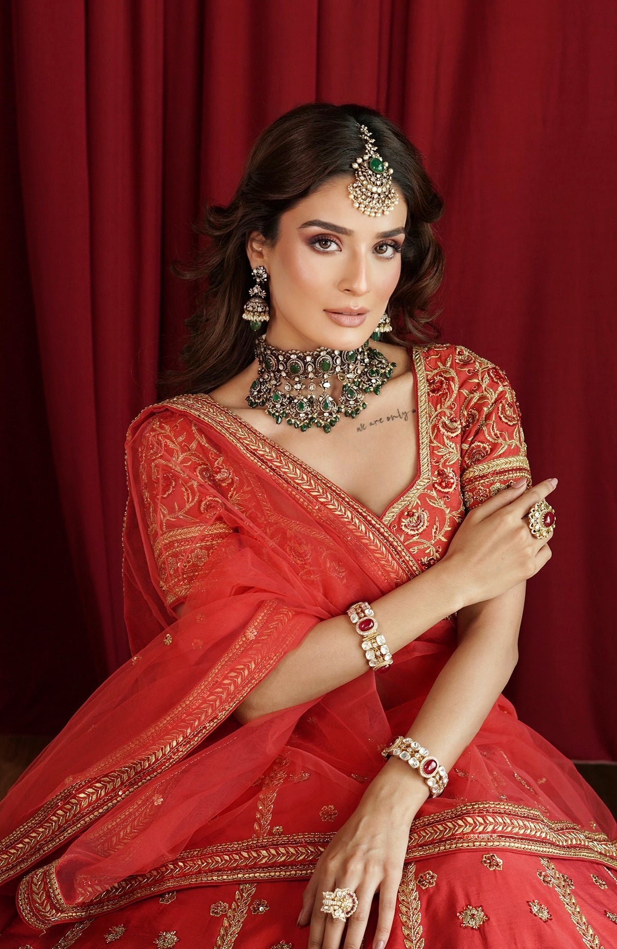 Scarlet red lehenga set with gold kasab and zardozi embroidery and a stylized V-neck blouse.