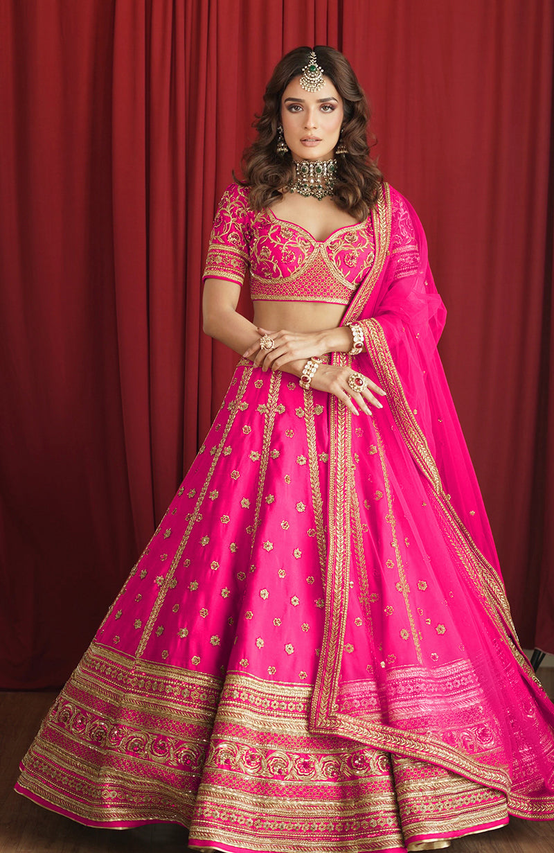 Scarlet red lehenga set with gold kasab and zardozi embroidery and a stylized V-neck blouse.