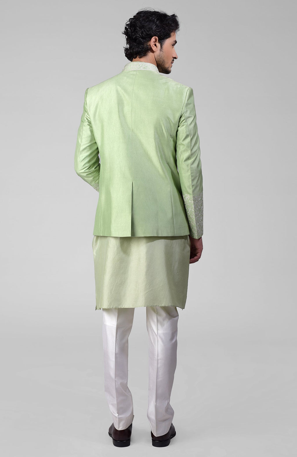 Sage green three-piece silk set with embroidered bandhgala jacket, kurta, and pants.