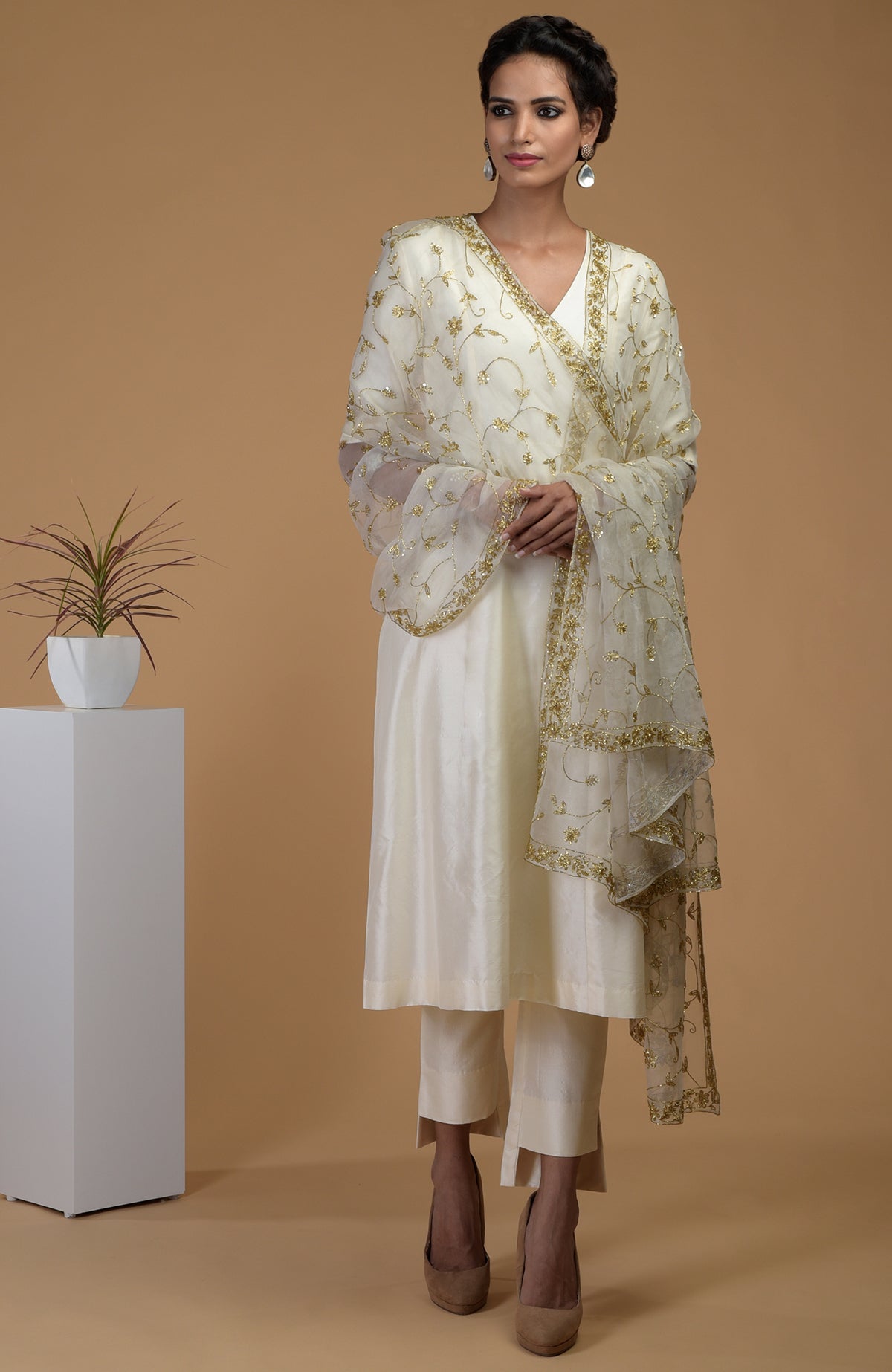 A model wears an ivory Matka silk kurta set with a gold zardozi embroidered organza dupatta.