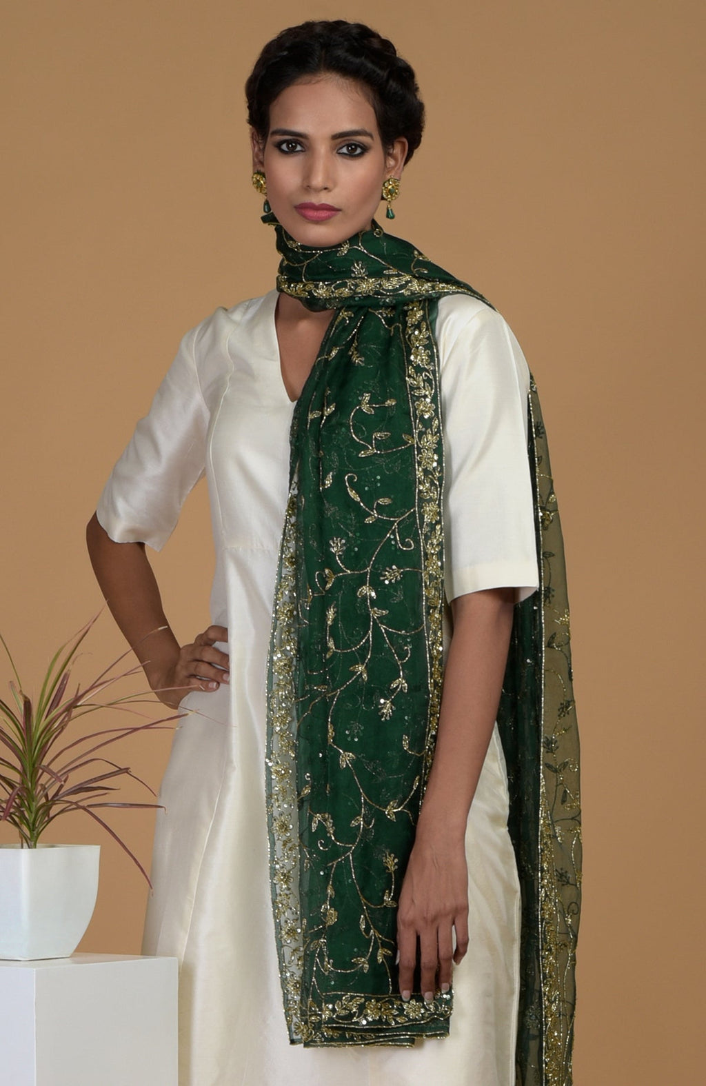 A woman models an ivory suit with an emerald green, embroidered dupatta.