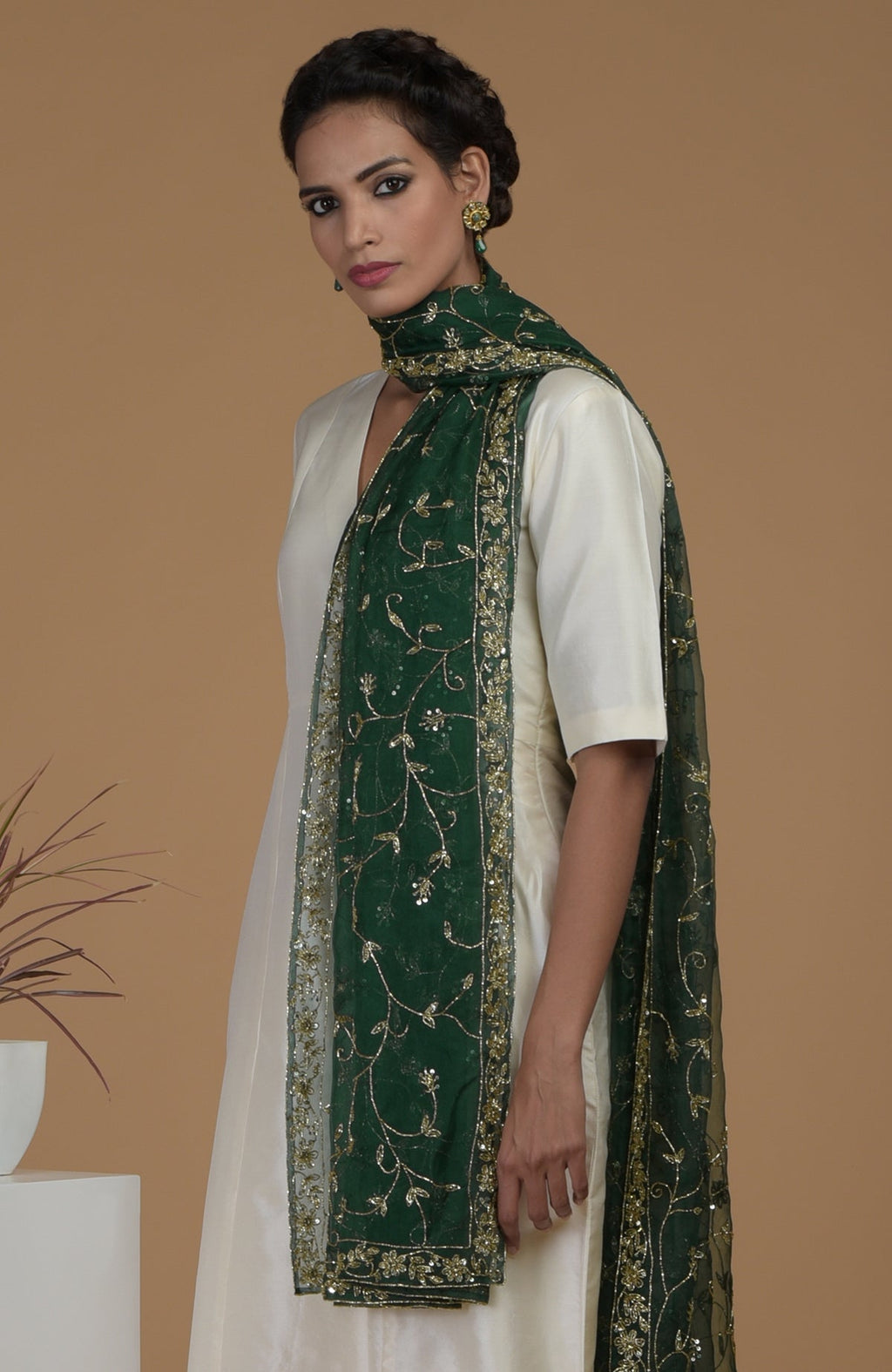 A woman models an ivory suit with an emerald green zardozi hand-embroidered dupatta.