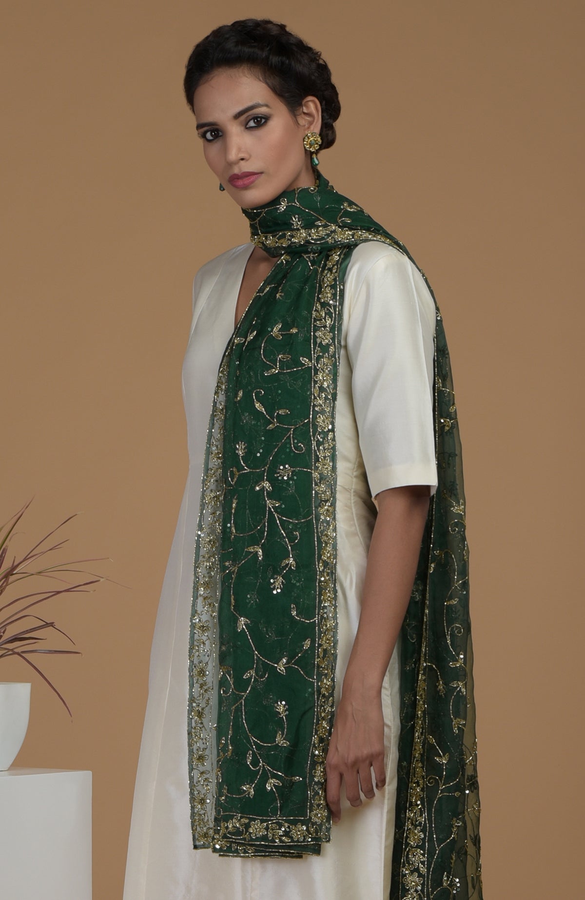 A woman models an ivory suit with an emerald green zardozi hand-embroidered dupatta.