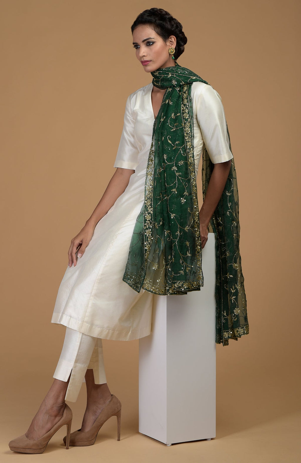 A woman in an ivory suit with an emerald green embroidered dupatta.