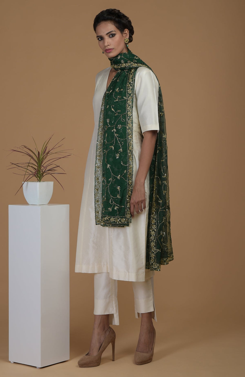 A woman models an emerald green zardozi hand-embroidered dupatta with a suit.
