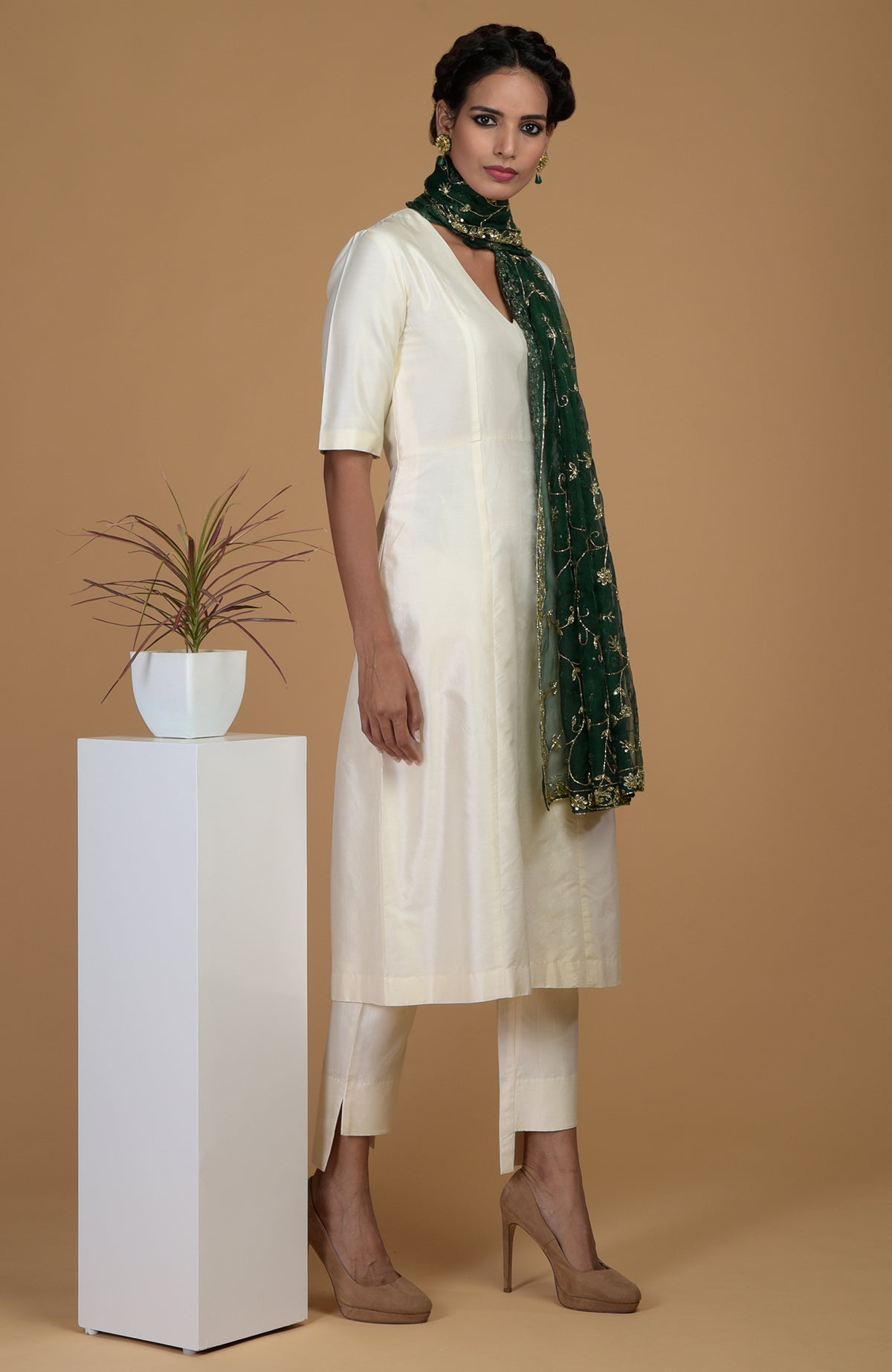 A woman models an ivory suit with an emerald green embroidered dupatta.