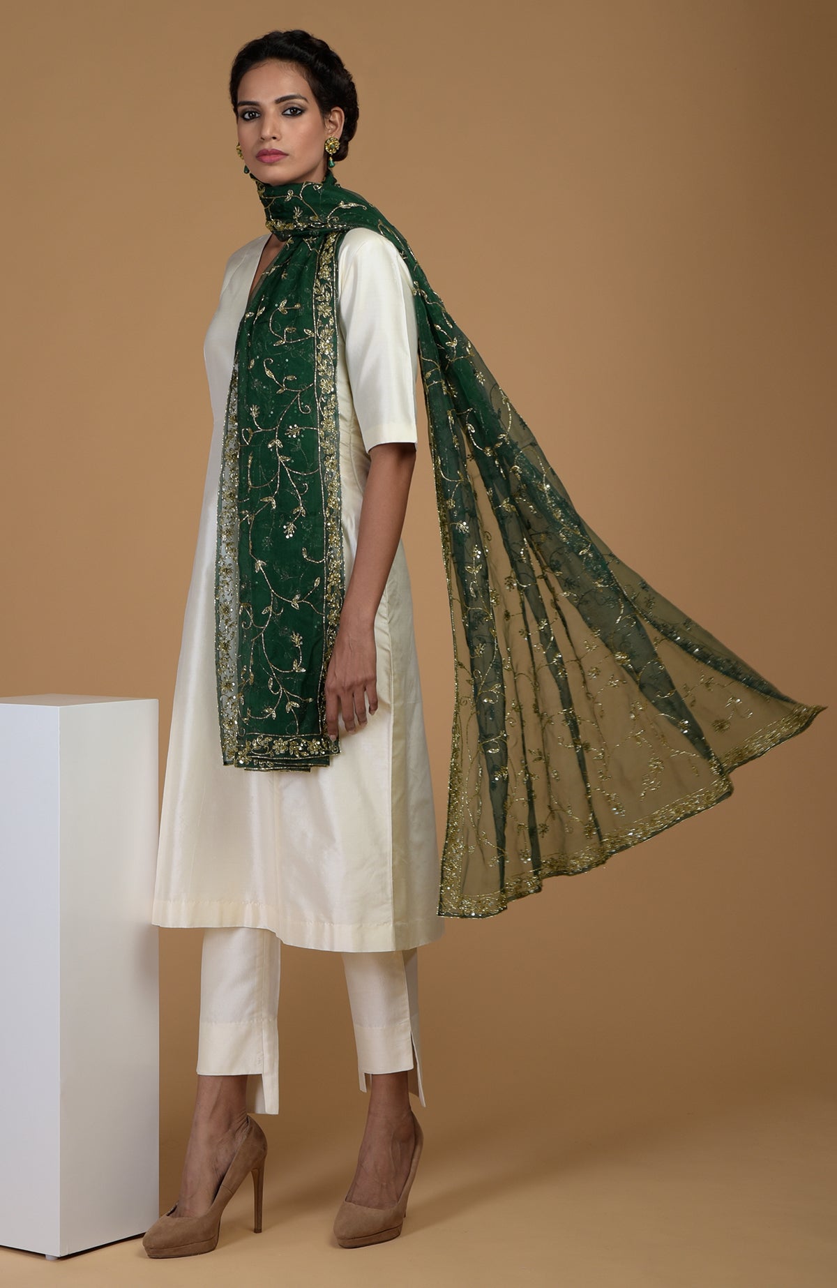 A woman in an ivory suit with an emerald green embroidered dupatta.