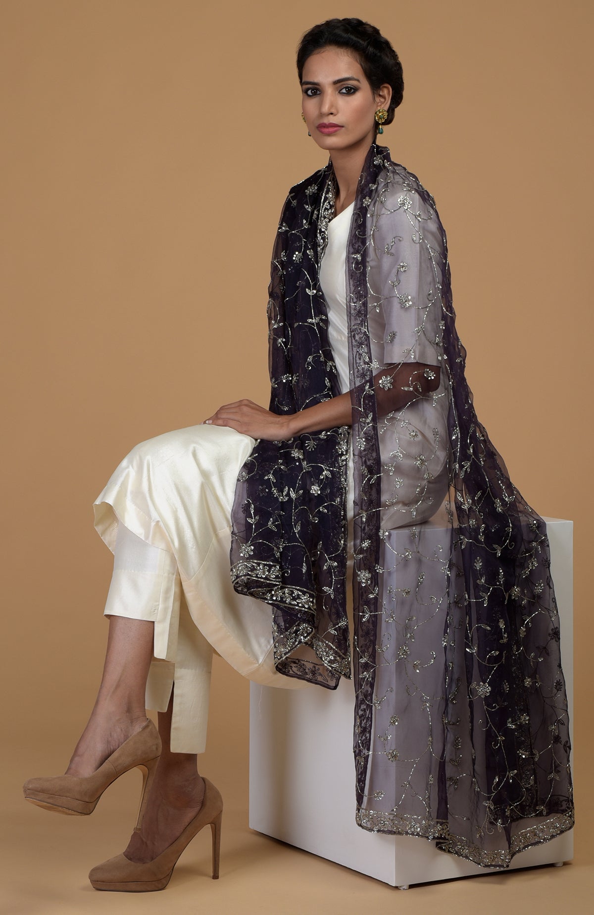 A woman in an eclipse blue zardozi hand-embroidered dupatta and ivory suit.