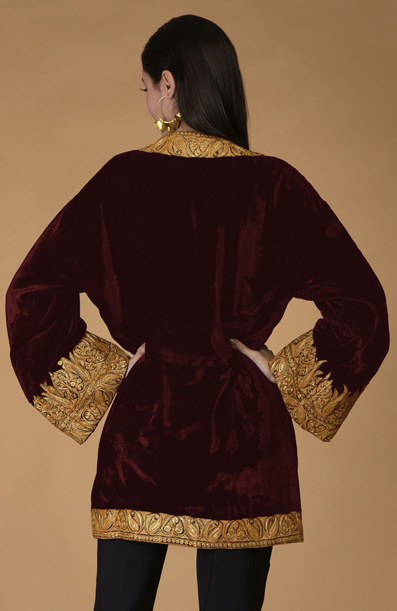 Burgundy velvet kimono jacket with gold Kashmiri tilla embroidery on the sleeves, hem, and neckline.