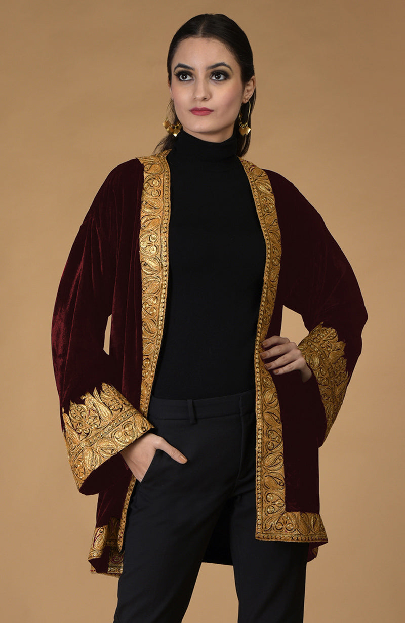 A woman models a burgundy velvet kimono jacket with gold Kashmiri tilla embroidery.