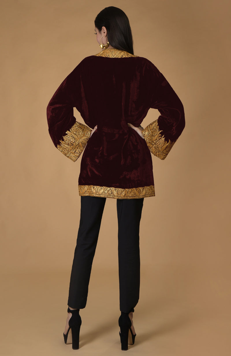 A woman models a burgundy velvet kimono jacket with gold tilla embroidery.