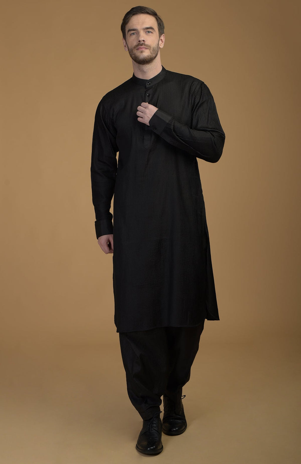 A man models a classic black silk Pathani kurta set with pintuck details.