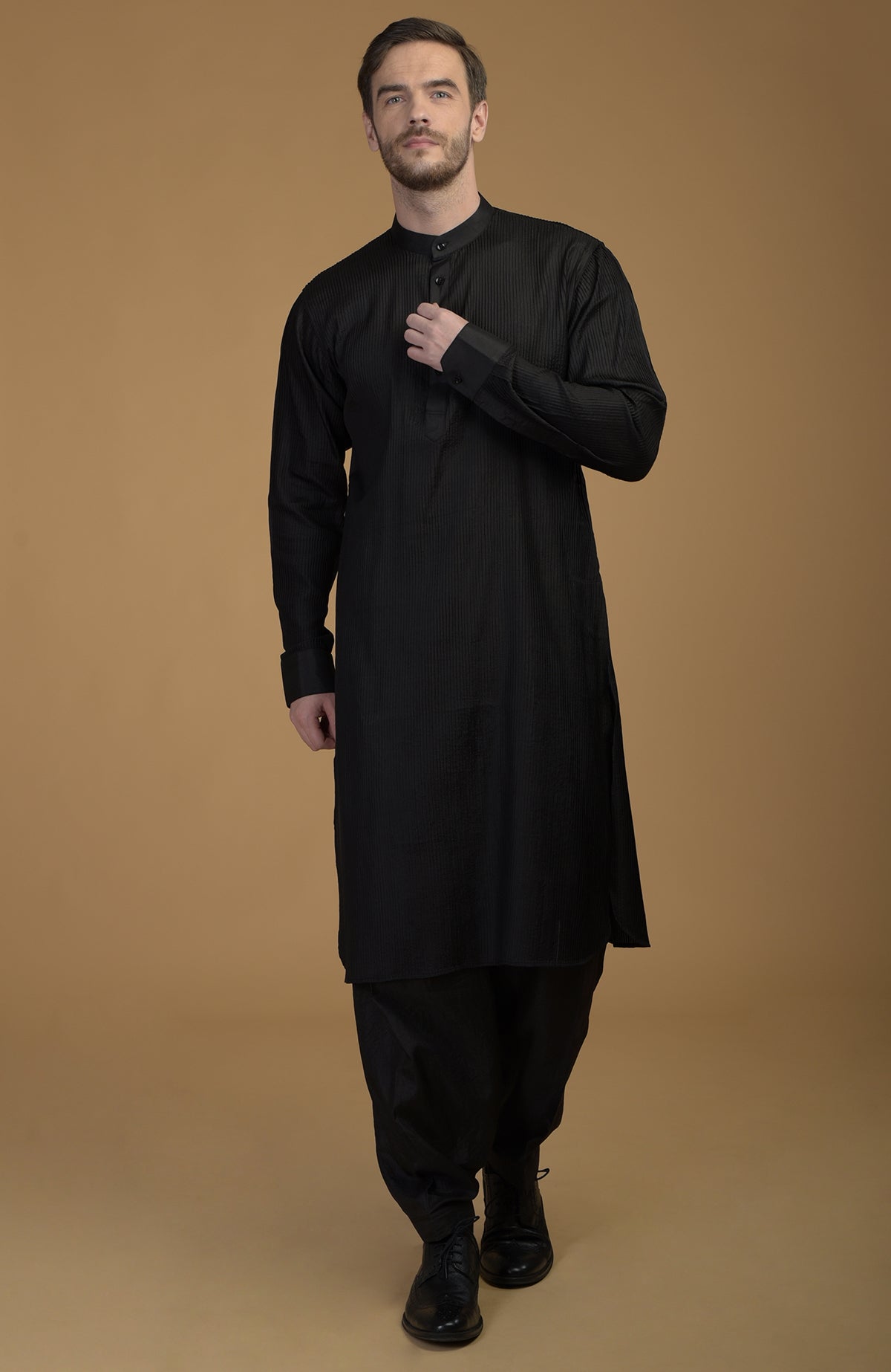 A man models a classic black silk Pathani kurta set with pintuck details.