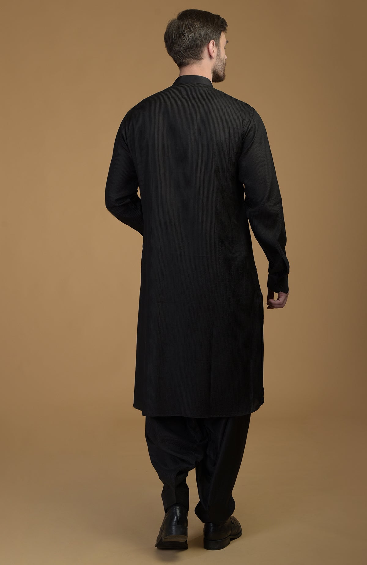 A man from behind wears a black silk Pathani kurta set with pintuck details.