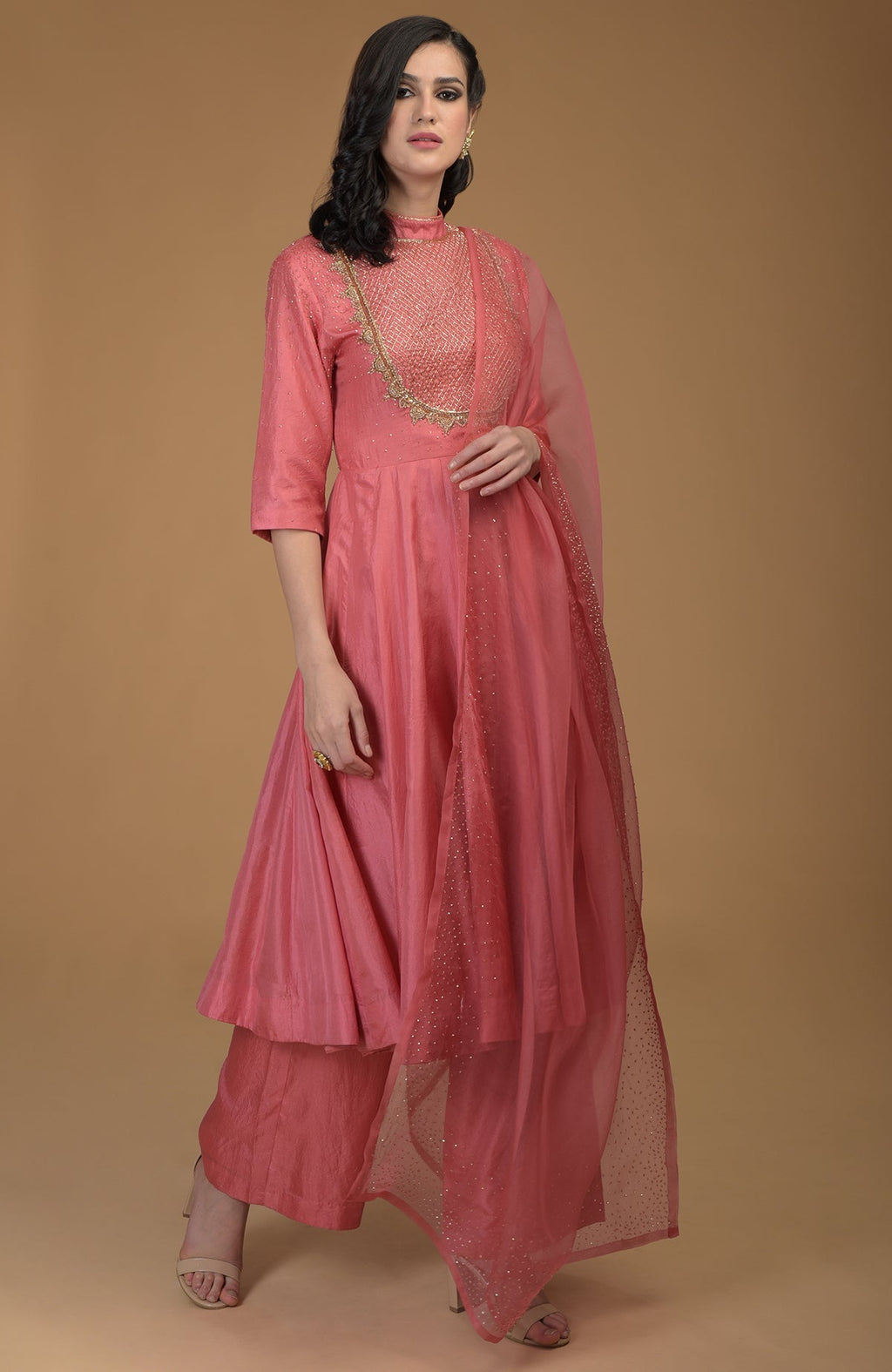 A woman models a peach echo kalidaar suit with zardozi hand embroidery.