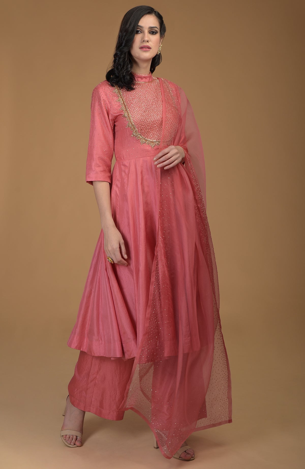 A woman models a peach echo kalidaar suit with zardozi hand embroidery.