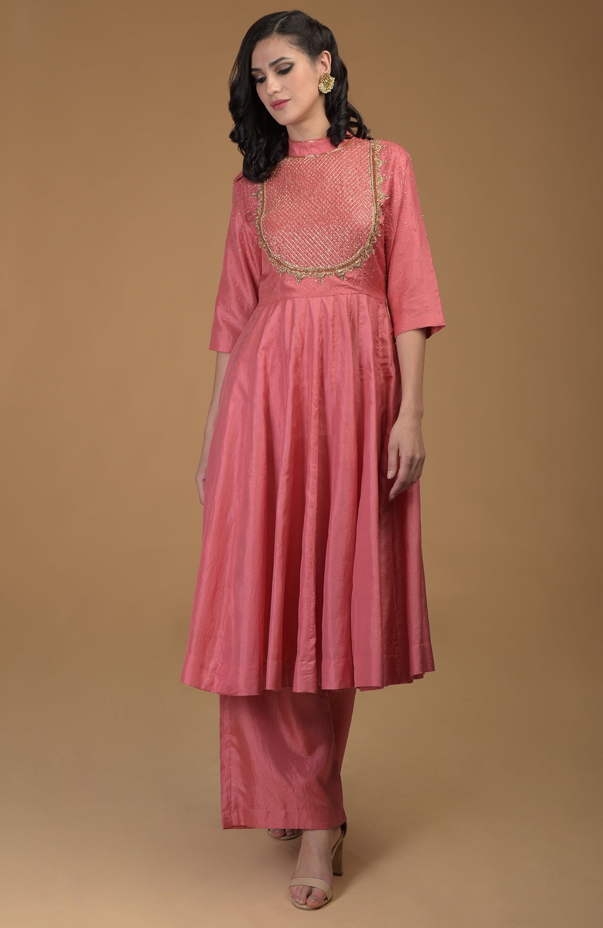 A woman models a peach echo kalidaar suit with zardozi hand embroidery.